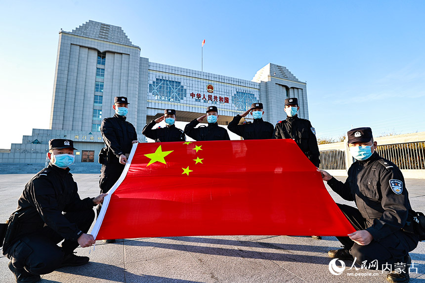 內(nèi)蒙古邊檢總站滿洲里邊檢站民警在國門下與國旗合影。盧兵兵攝