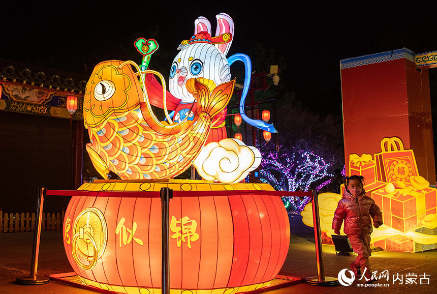 1月18日晚，小朋友在呼和浩特市玉泉區(qū)塞上老街歷史文化街區(qū)的“玉兔”花燈旁游玩。丁根厚攝