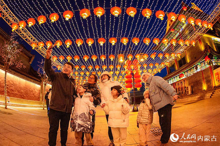 1月18日晚，游客在呼和浩特市玉泉區(qū)塞上老街歷史文化街區(qū)燈籠長廊下自拍留影。丁根厚攝