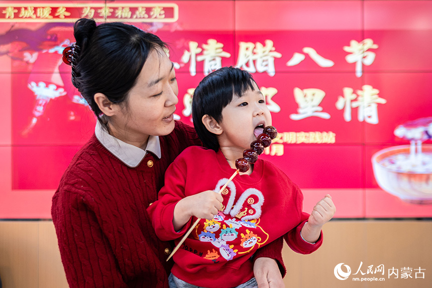 呼和浩特市玉泉區(qū)清泉街社區(qū)小朋友在臘八節(jié)活動現(xiàn)場品嘗糖葫蘆。丁根厚攝