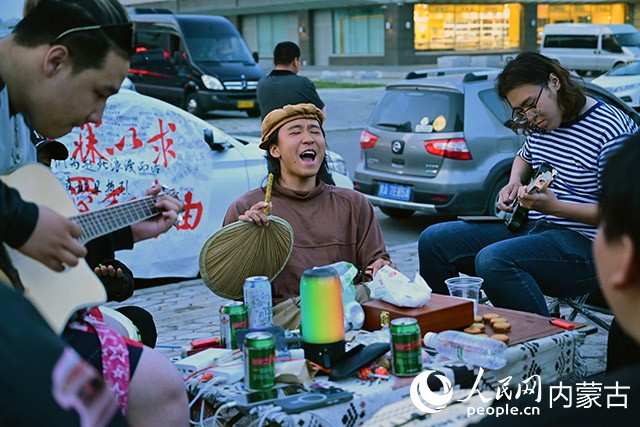 葉鎮(zhèn)豪（左二）與滿洲里當?shù)氐哪贻p人在街頭高歌。人民網(wǎng)記者 寇雅楠攝