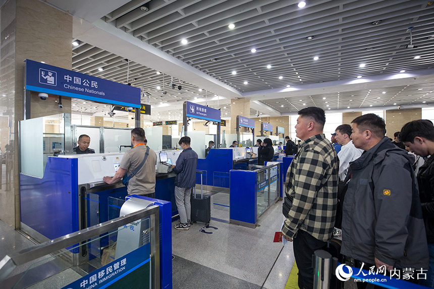 二連出入境邊防檢查站移民管理警察有序?yàn)槁每娃k理通關(guān)手續(xù)。郭鵬杰攝