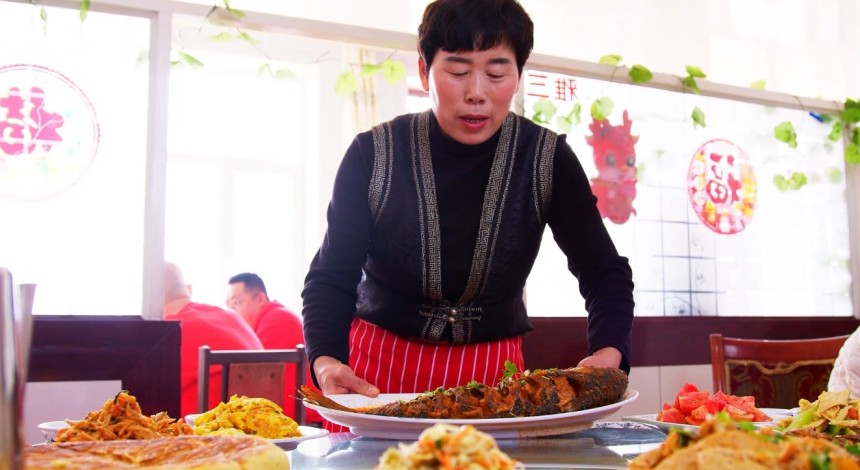 郝家窯村一家農(nóng)家樂餐廳經(jīng)營者正在為游客端上剛燉好的托縣鯉魚。王建宏攝