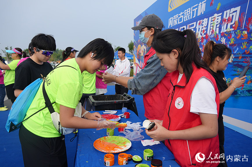 選手參與在主題背景板上按手印打卡。實(shí)習(xí)生 王正玉攝