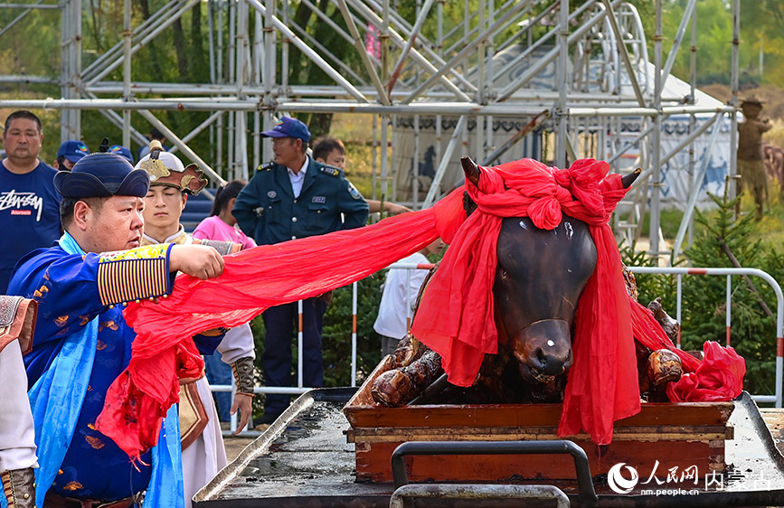 10月4日，民間藝人在鄂爾多斯市伊金霍洛旗鄂爾多斯文化產(chǎn)業(yè)園為烤全牛剪彩。王正攝