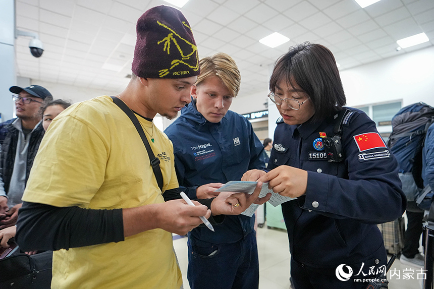 二連出入境邊防檢查站移民管理警察正在為入境旅客提供通關(guān)咨詢。楊金燁攝