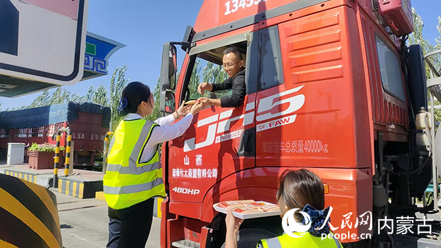 10月6日，內(nèi)蒙古交通集團巴彥淖爾分公司臨河新區(qū)收費所工作人員將月餅送到貨車司機手中。內(nèi)蒙古自治區(qū)交通運輸廳供圖