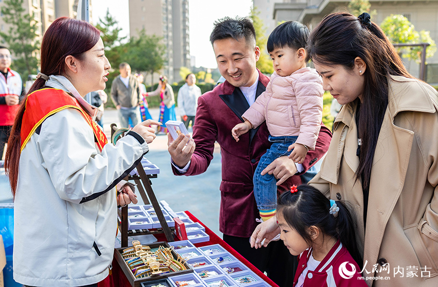 呼和浩特市玉泉區(qū)“文明市集”主題活動現(xiàn)場，社區(qū)居民在了解“敕勒川巧娘”民族手工藝品。丁根厚攝