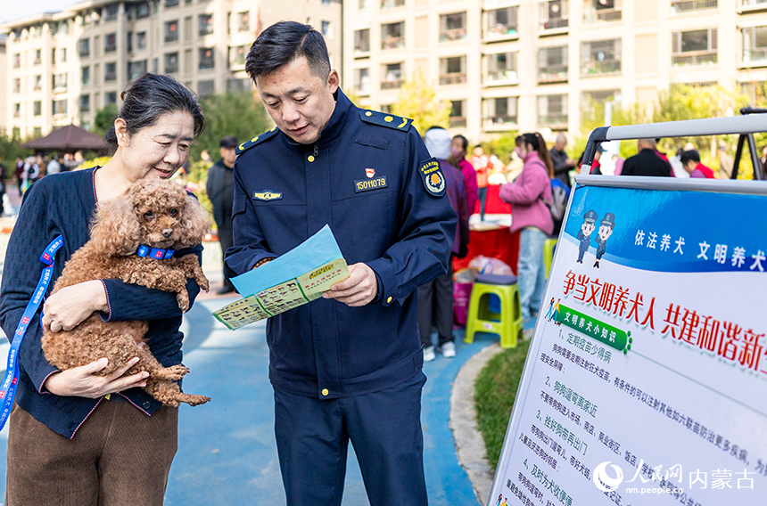 呼和浩特市玉泉區(qū)“文明市集”主題活動(dòng)現(xiàn)場(chǎng)，城管隊(duì)員給居民講解文明養(yǎng)犬知識(shí)。丁根厚攝