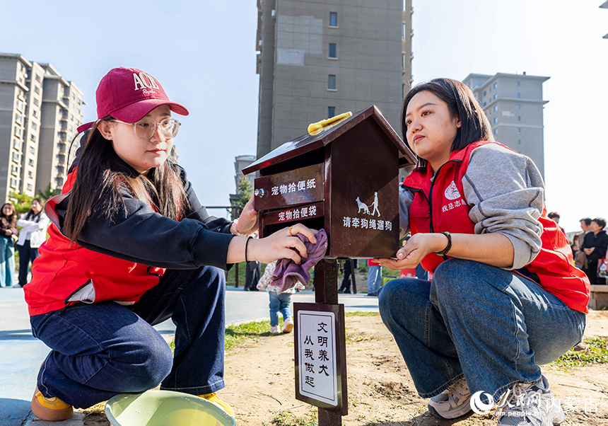 呼和浩特市玉泉區(qū)“文明市集”主題活動(dòng)現(xiàn)場(chǎng)，志愿者在擦拭“文明養(yǎng)犬”寵物便民箱。丁根厚攝