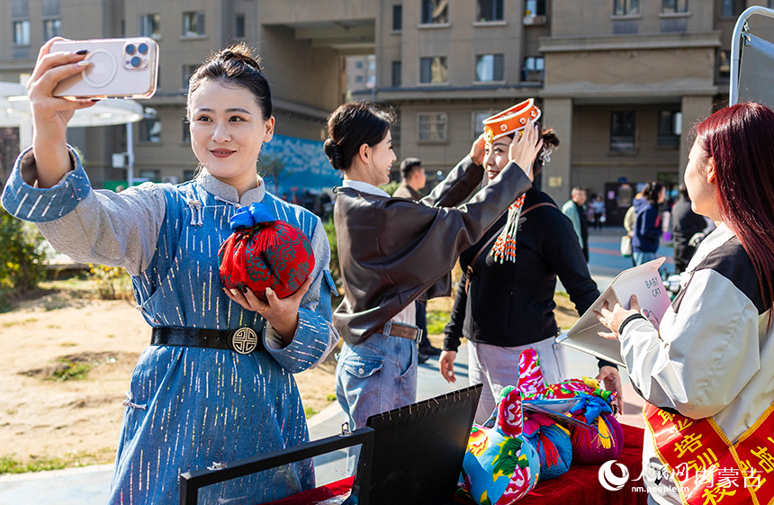 呼和浩特市玉泉區(qū)“文明市集”主題活動(dòng)現(xiàn)場，烏蘭牧騎隊(duì)員在了解“敕勒川巧娘”民族手工藝品。丁根厚攝