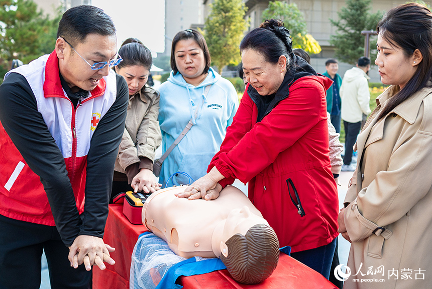 呼和浩特市玉泉區(qū)“文明市集”主題活動(dòng)現(xiàn)場(chǎng)，社區(qū)居民在紅十字志愿者指導(dǎo)下學(xué)習(xí)應(yīng)急救護(hù)技能。丁根厚攝