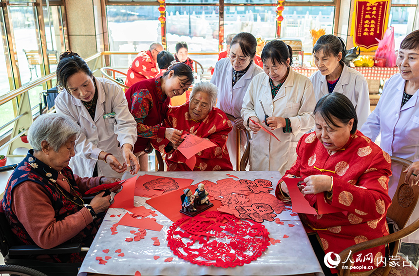 護(hù)理員陪伴老人們?cè)诤艉秃铺厥杏袢獏^(qū)民政局“愛心敬老 情暖重陽(yáng)”主題活動(dòng)現(xiàn)場(chǎng)一起剪紙。丁根厚攝