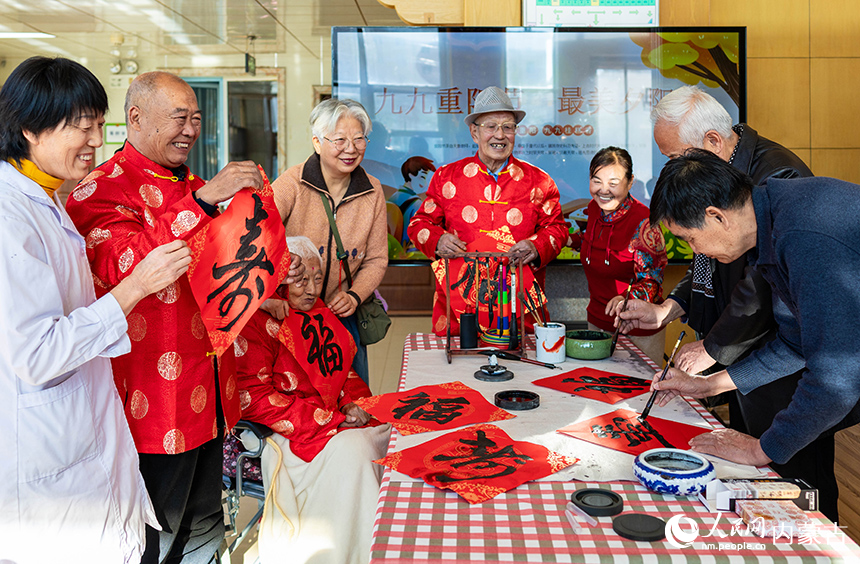 文化志愿者在呼和浩特市玉泉區(qū)民政局“愛心敬老 情暖重陽”主題活動現(xiàn)場為老人們書寫“壽”字書法作品。丁根厚攝