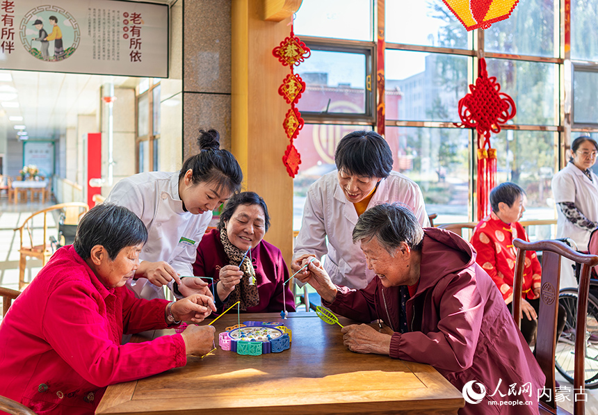護(hù)理員陪伴老人們在呼和浩特市玉泉區(qū)民政局“愛心敬老 情暖重陽”主題活動現(xiàn)場玩益智游戲。丁根厚攝