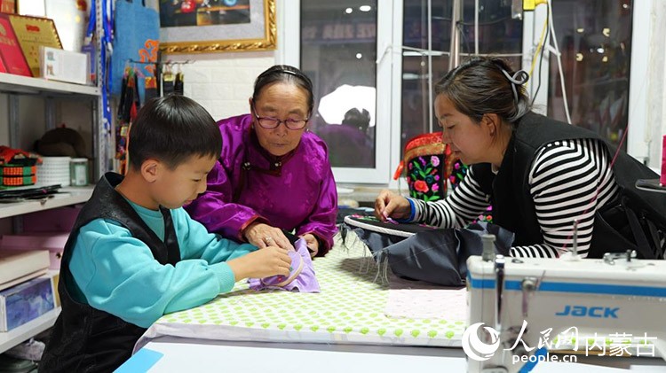 71歲的薩仁格樂(lè)正教著她的女兒和外孫做蒙古靴刺繡。蘇米雅攝