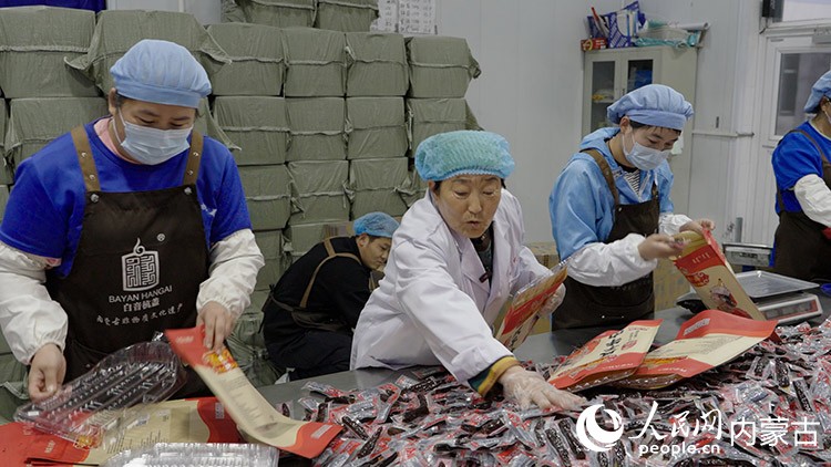 白秀枝在非遺工坊的包裝車間和工人一起包裝牛肉干。李旭明 攝