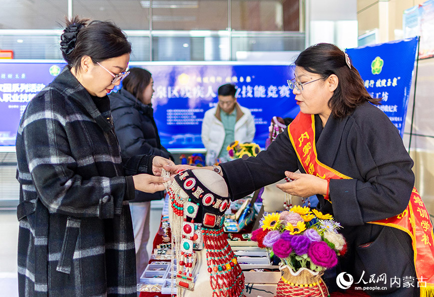 11月16日，呼和浩特市玉泉區(qū)殘疾人職業(yè)技能競賽現(xiàn)場，市民在殘疾人就業(yè)成果展示區(qū)了解一款“敕勒川巧娘”手工藝品。丁根厚攝
