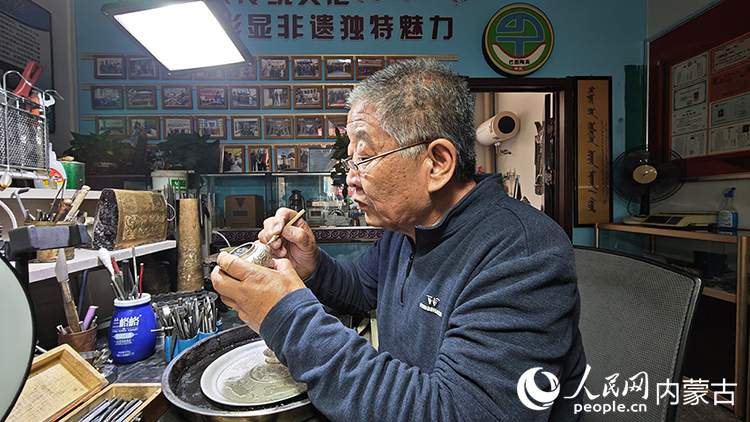 國家級非物質(zhì)文化遺產(chǎn)代表性項(xiàng)目烏拉特銅銀器制作技藝傳承人巴圖陶高對制作的銀盤進(jìn)行鏨刻。人民網(wǎng)記者 張雪冬攝