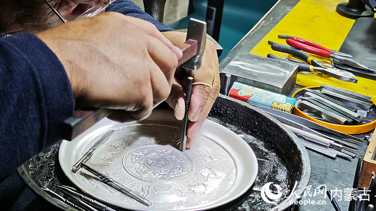 國家級非物質(zhì)文化遺產(chǎn)代表性項(xiàng)目烏拉特銅銀器制作技藝傳承人巴圖陶高對制作的銀盤進(jìn)行鏨刻。人民網(wǎng)記者 張雪冬攝