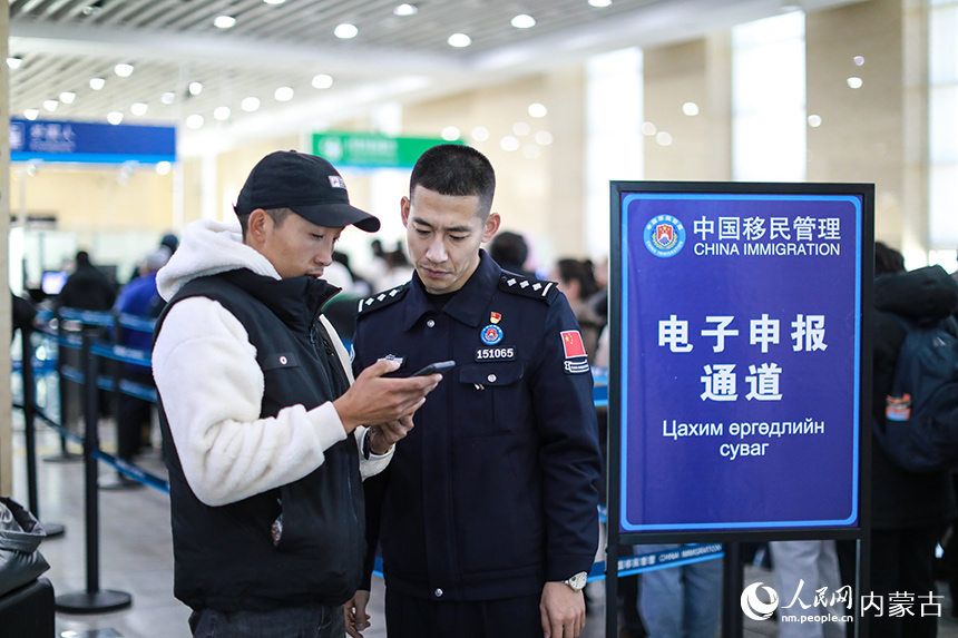 二連出入境邊防檢查站移民管理警察協(xié)助蒙古國旅客網(wǎng)上填報外國人入境卡。郭鵬杰攝