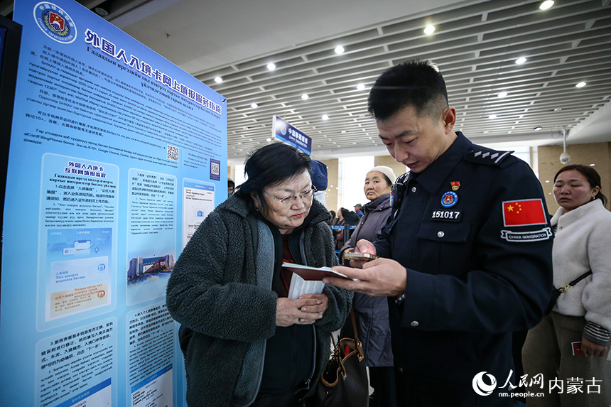 二連出入境邊防檢查站移民管理警察協(xié)助蒙古國旅客網(wǎng)上填報外國人入境卡。郭鵬杰攝